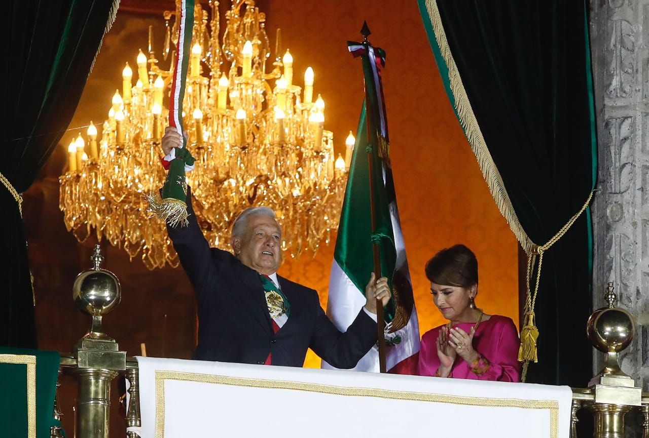 El presidente mexicano enarbolando la bandera mexicana.